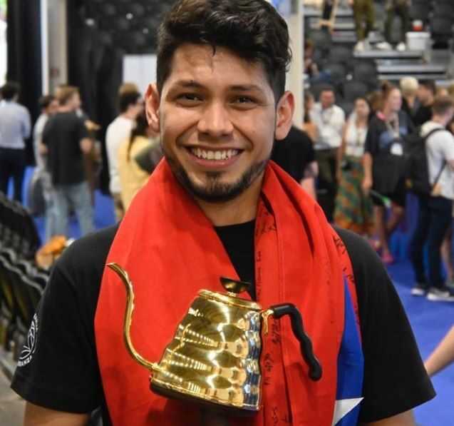Carlos Medina sosteniendo un trofeo con forma de tetera dorada.